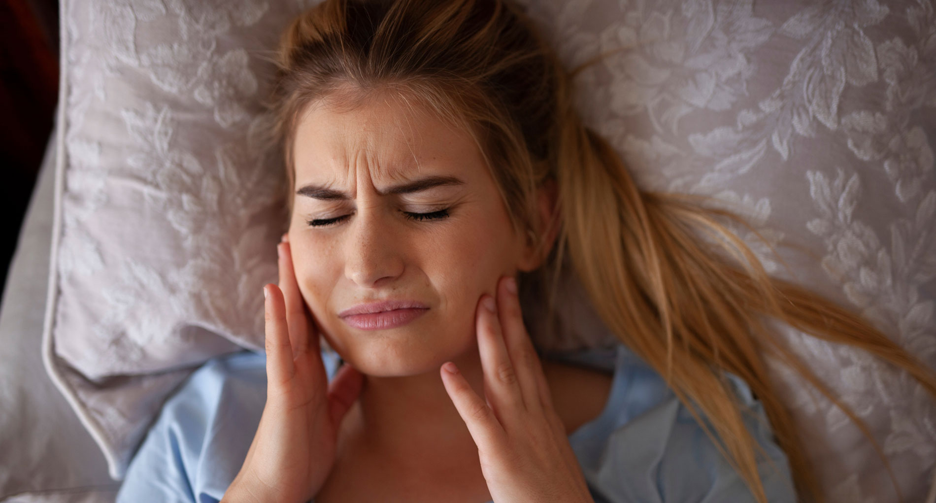 Una mujer sufre dolor mandíbular en la cama por culpa del bruxismo